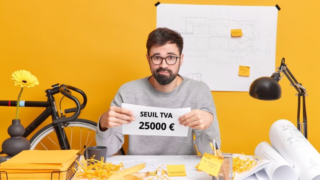 Un micro-entrepreneur montre une affiche où est écrit : Seuil TVA 25000 €