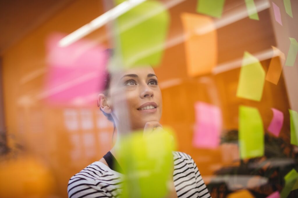 Une entrepreneuse devant un tableau de post-it sur lequel se trouve les différentes soft skills